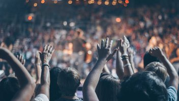 Une foule de personnes lève les mains dans un évènement.